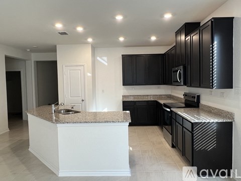 A kitchen with black cabinets and a granite countertop.