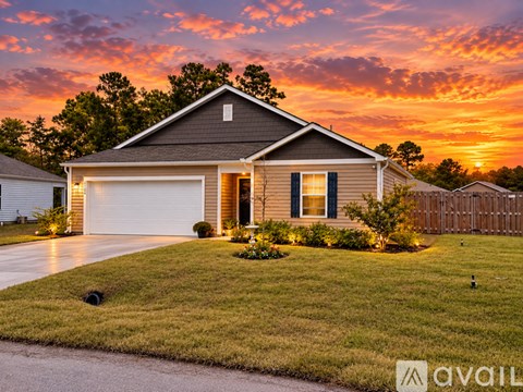 A house with a garage and a driveway is shown in front of a sunset.