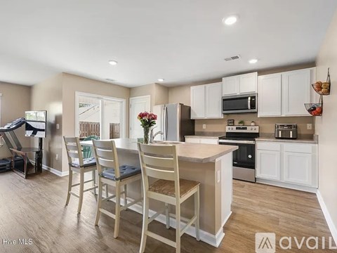 A kitchen with white cabinets and a wooden island.