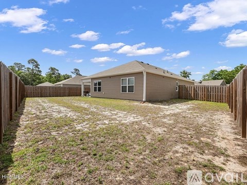 A house with a brown fence and a brown roof is surrounded by a grassy area.