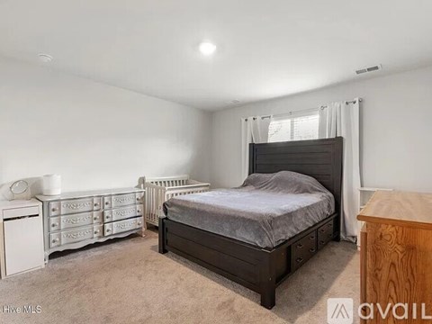 A bedroom with a bed, dresser, and nightstand.