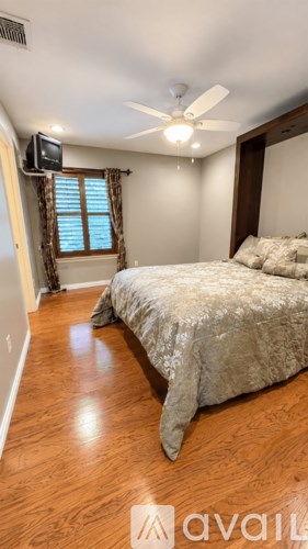 A bedroom with a bed, a ceiling fan, and a window with blinds.