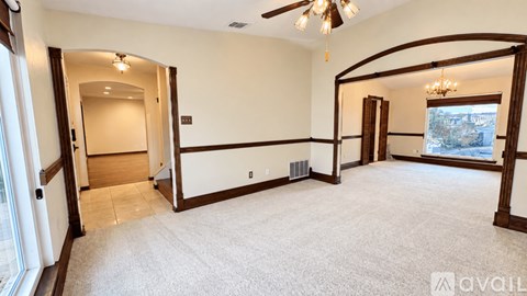 A spacious room with a carpeted floor and a ceiling fan.