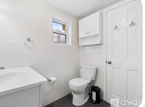 A white toilet in a small bathroom with a window.