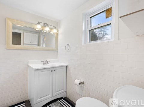 A white bathroom with a mirror, sink, and toilet.