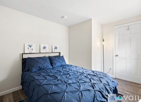 A bedroom with a bed covered in a blue comforter.