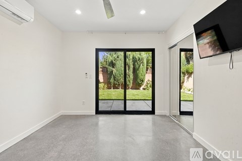 A spacious room with a sliding glass door leading to a backyard.
