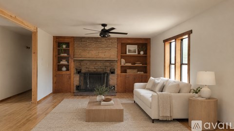 A living room with a fireplace, a couch, and a fan.
