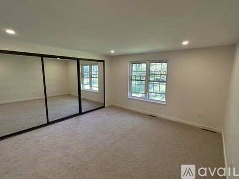 A spacious room with carpeted floor and large windows.