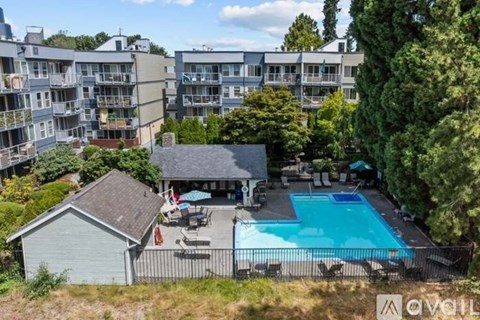 A pool surrounded by a fence and chairs in a backyard.