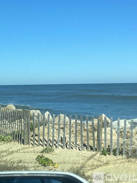 A wooden fence runs along the edge of a sandy beach.