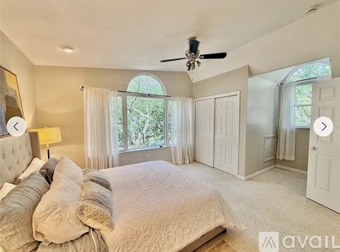A bedroom with a large bed and a ceiling fan.