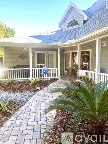 A house with a white porch and a brick walkway.