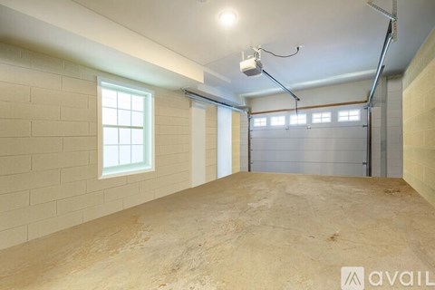 A spacious garage with a concrete floor and walls, equipped with a garage door opener.