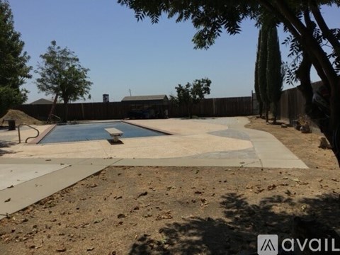 A pool surrounded by a concrete patio and trees.
