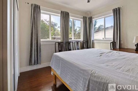 A bedroom with a large bed and a window with curtains.