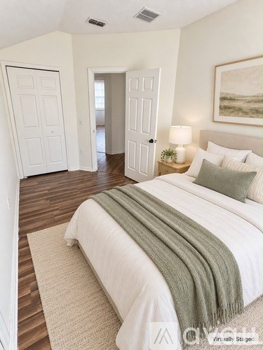 A bedroom with a large bed and a painting on the wall.