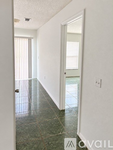 A hallway with a green marble floor and white walls.