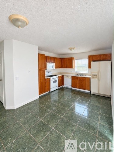 A kitchen with white appliances and wooden cabinets.