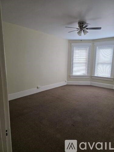 A room with a carpeted floor and a ceiling fan.