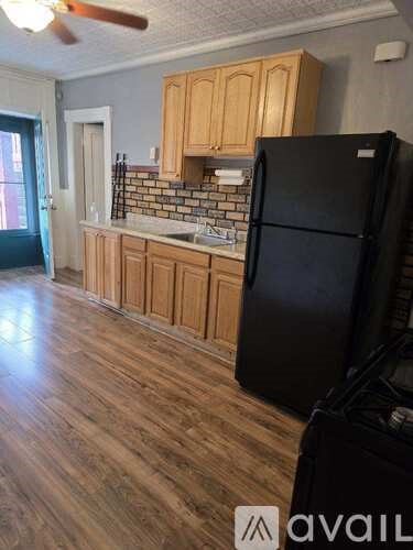 A kitchen with wooden cabinets and a black refrigerator.