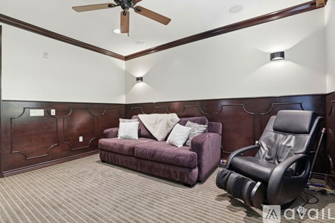 A living room with a purple couch and a black recliner.