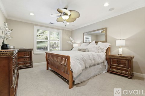 A bedroom with a large bed, a dresser, and a ceiling fan.