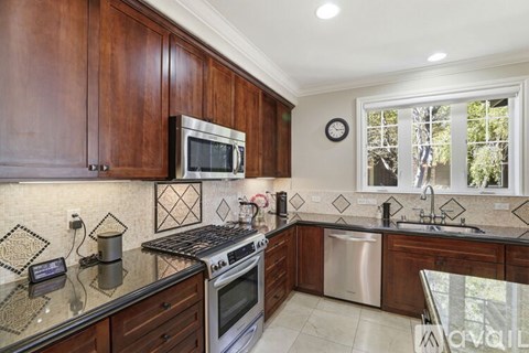 A kitchen with dark wood cabinets and a stainless steel stove.