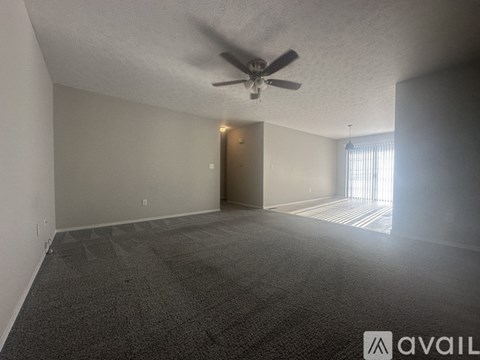 A room with a carpeted floor and a ceiling fan.