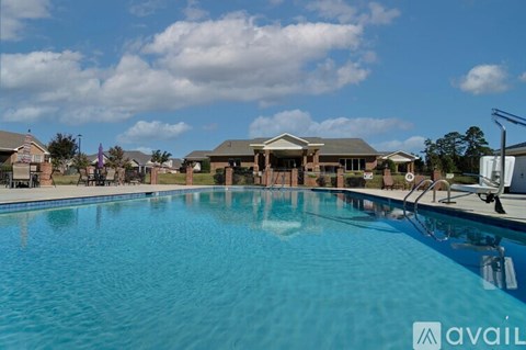 A large swimming pool in front of a building with a clear blue sky above.
