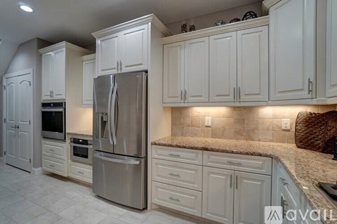 A kitchen with white cabinets and a stainless steel refrigerator.