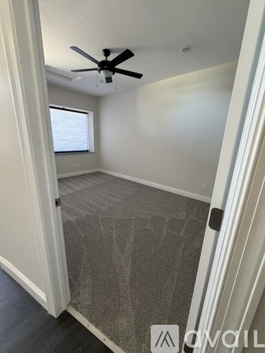 A room with a ceiling fan and a doorway leading to another room.