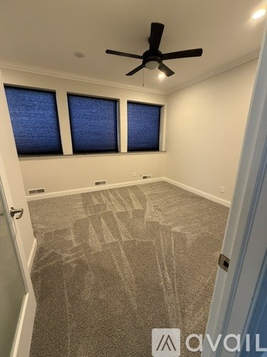 A room with a carpeted floor and a ceiling fan.