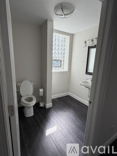 A bathroom with a toilet, sink, and window.
