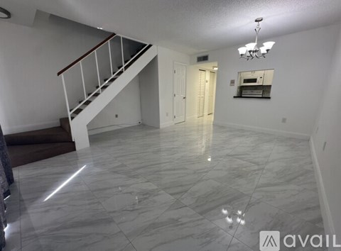 A spacious room with marble flooring and a staircase.