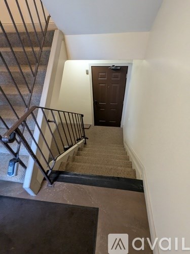 A staircase with a metal railing and a brown carpeted runner.