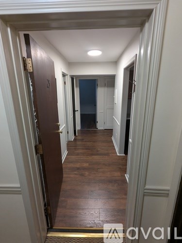 A hallway with a wooden floor and white walls.