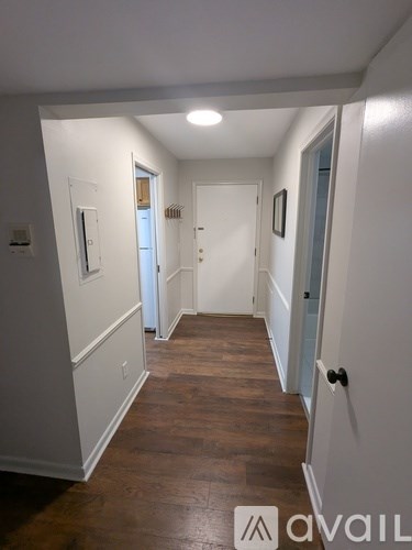 A hallway with wood floors and white walls.