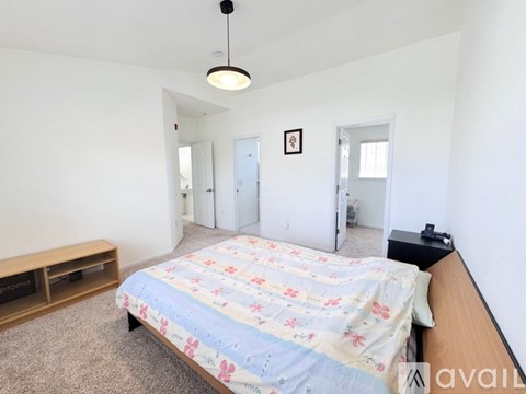 A bedroom with a bed, dresser, and a hanging light fixture.