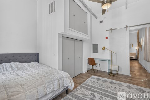 A bedroom with a large bed and a chair in front of a desk.