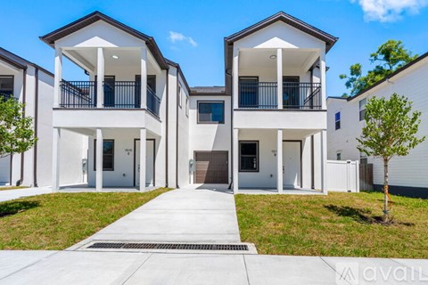A modern two-story apartment building with white exteriors and black railings.