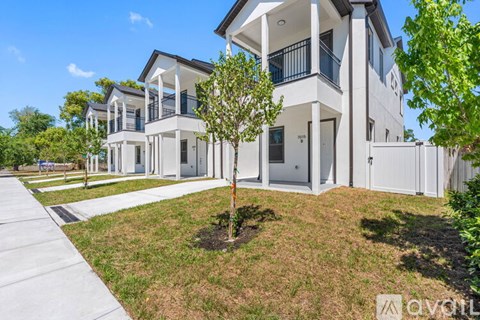 A white two-story house with a balcony on the second floor.