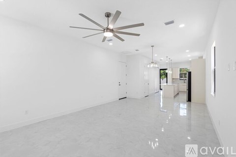 A spacious, empty room with a ceiling fan and a glossy floor.