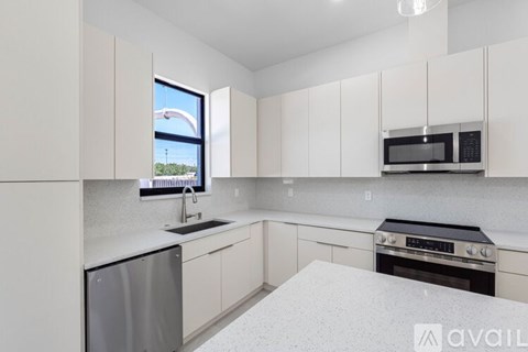 A kitchen with white cabinets and a window overlooking a building.