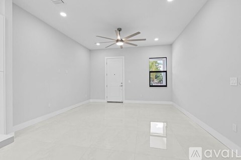 A spacious room with a ceiling fan and a door.