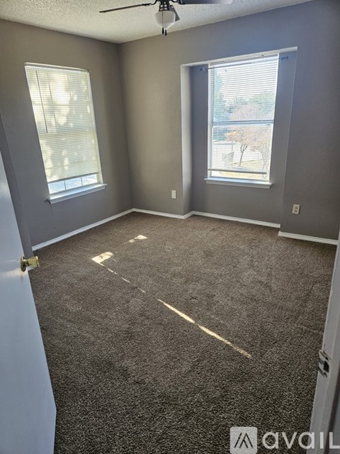 A room with grey walls and carpeted floor with a ceiling fan.