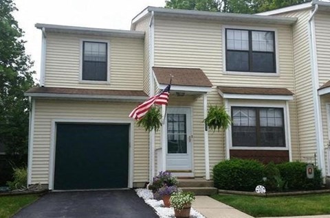 A house with a garage and an American flag hanging on the front door.