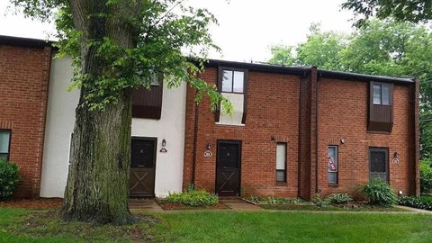 A red brick building with a tree in front.