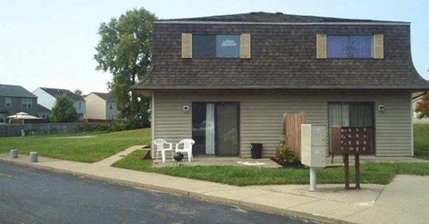 A house with a grey roof and a white chair in front of it.