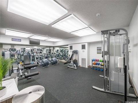A well-lit gym with various exercise equipment.